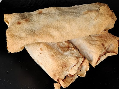 Three rolled up tortillas on a black surface.