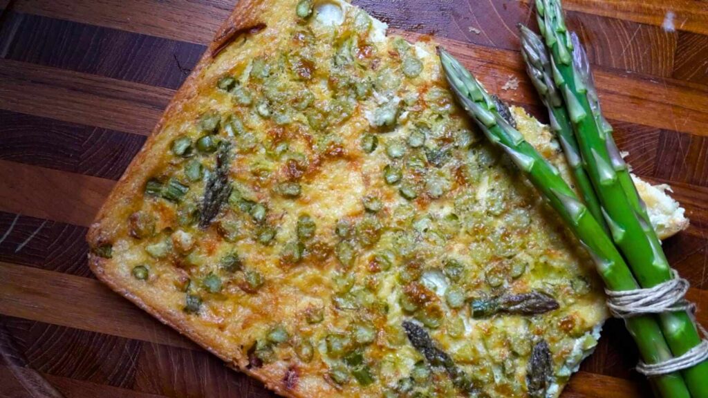 Rectangular asparagus pizza on a wooden cutting board.